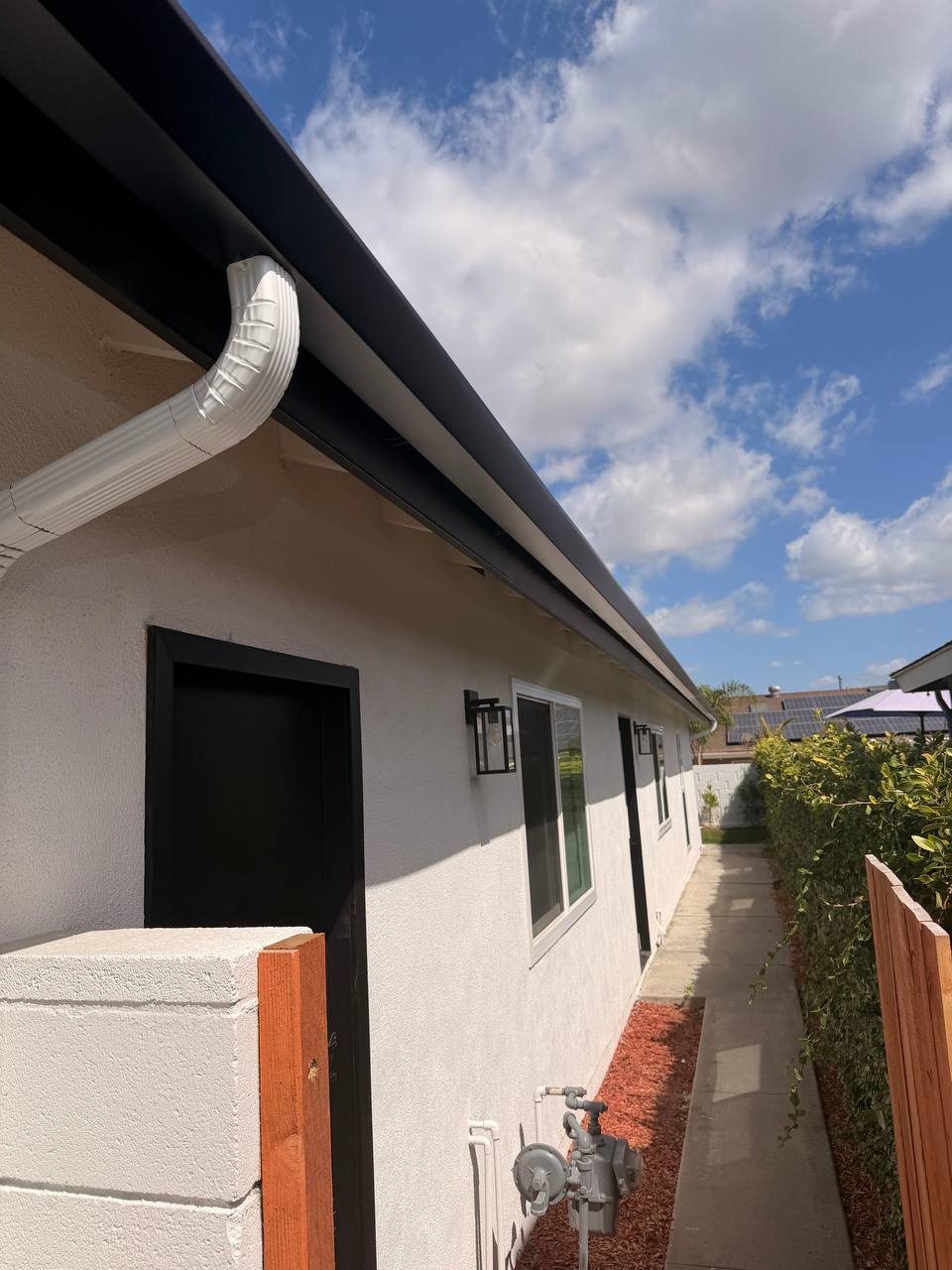 Modern black home with seamless black aluminum gutters and decorative rain chain, Orange County